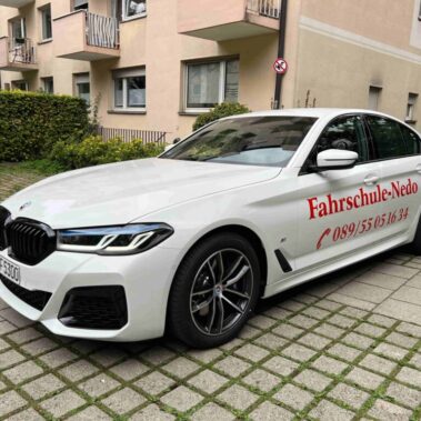 Seitenansicht des BMW 5er Fahrschulautos mit Logo und Telefonnummer der Fahrschule Nedo.